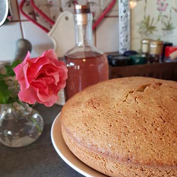 Sciogliere il burro e unirlo allo zucchero. Aggiungere le uova, uno alla volta. Unire il succo e la scorza di mezza arancia. Tritare finemente i pistacchi e le mandorle, unirli all’impasto insieme alla farina, alla fecola e al lievito setacciati. Cuocere in una teglia imburrata e infarinata di 21 cm per 40 minuti a 180 °C. Preparare la glassa: stemperare lo zucchero a velo con l’acqua alle rose e l’acqua naturale. Io ho aggiunto una goccia di colorante alimentare rosa per dare un po’ di colore alla glassa. Versare la glassa sulla torta e decorare subito con pistacchi tritati e petali di rosa.